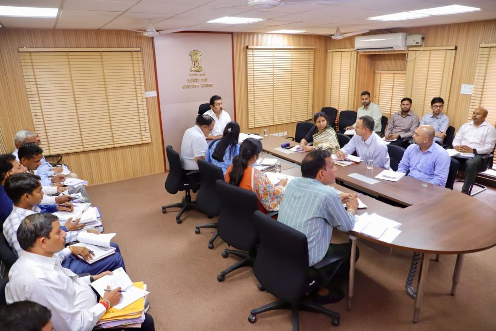 Sports Minister Col. Rajyavardhan Rathore interacting inspiringly with young track and field athletes at a modern sports stadium.